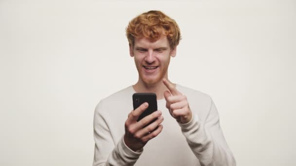 Kızıl Saçlı Genç Adam Cep Telefonuna Bakarken Baş Parmağını Kaldırarak — Stok video