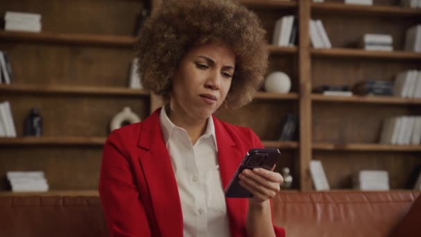 穿着红色西装的职业女性在现代办公室里阅读短信时 会做出令人困惑的表情 — 图库视频影像