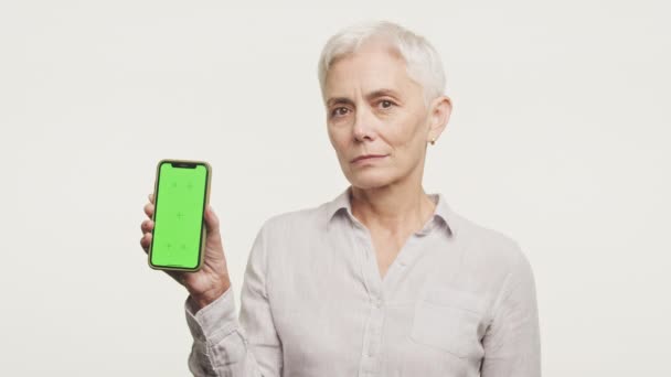 Зріла Жінка Показує Мобільний Телефон Зеленим Екраном Ідеально Підходить Макетів — стокове відео