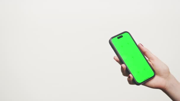 手拿手机 白色背景上有彩色绿色屏幕 — 图库视频影像