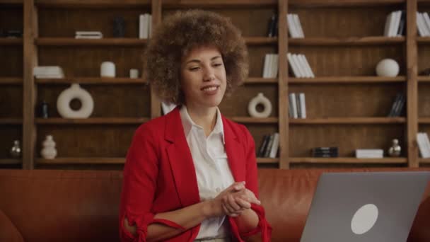 Lächelnde Frau Mit Lockigem Haar Roter Anzugjacke Spricht Einer Telefonkonferenz — Stockvideo