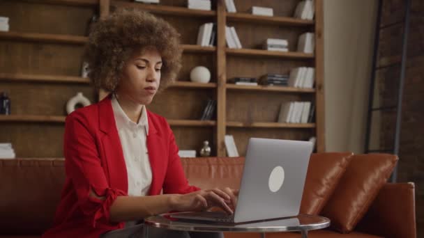 快乐的女商人 卷曲的头发 在舒适的工作空间里用笔记本电脑 流露出积极的一面 — 图库视频影像
