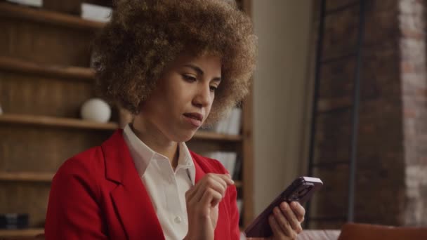 穿着红色西装的女商人在上网浏览智能手机 办公室内饰时陷入了沉思 — 图库视频影像