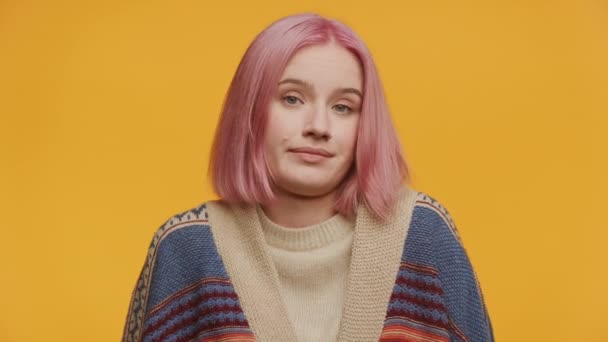 黄色い背景の前にポーズする思慮深い表情を示すピンクの髪の肩を持つ若い女性 — ストック動画