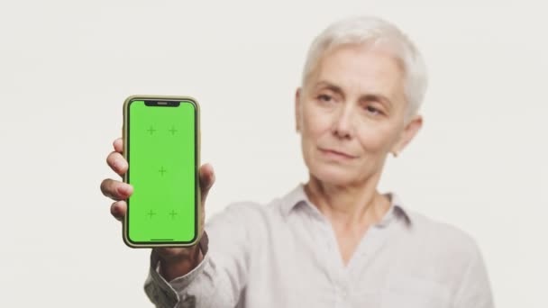 Ältere Frau Präsentiert Ein Smartphone Mit Grünem Bildschirm Mit Chroma — Stockvideo