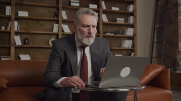 Зрелый Бизнесмен Костюме Внимательно Рассматривает Контент Ноутбуке Вызывая Чувство Фокуса — стоковое видео