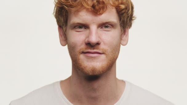 一个有着卷曲红头发 中性表情和白皙皮肤的自信男子的特写肖像 背景为白色 — 图库视频影像