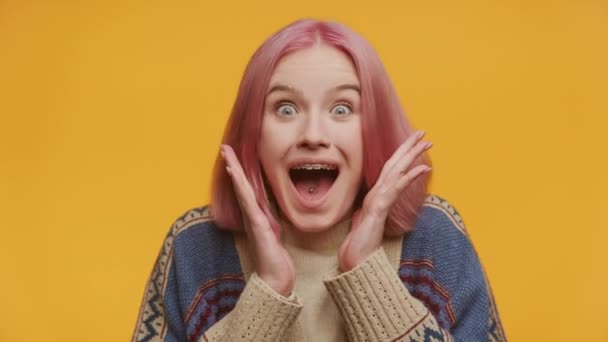 鮮やかなピンクの髪を持つジョイスフルな女性は 驚くような表情 見えるブレース 黄色の背景に手を組み立てた顔を示しています — ストック動画