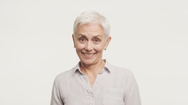一个快乐的老年妇女的画像 一头时髦的短而白的头发 灰色的衬衫点头表示同意 与白色背景隔离 — 图库视频影像