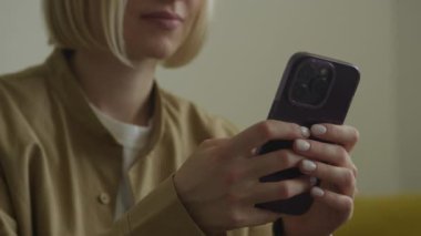 Şık bir çantada akıllı telefon kullanan kısa saçlı bir kadının kırpılmış görüntüsü.