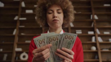 Birkaç yüz dolarlık banknot tutan kadın, ofis ortamında finansal konsept.
