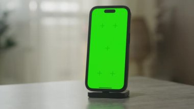 Standın üzerine monte edilmiş bir akıllı telefon, özel içerik için uygun bir krom anahtar yeşil ekran görüntüler