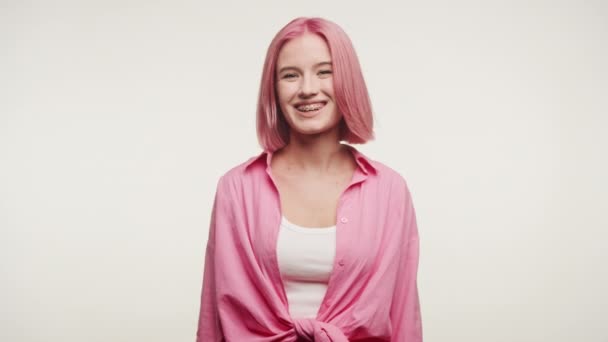 年轻而快乐的女人 一头时髦的粉红头发 一边微笑着 一边摆出姿势 一边在电视电话会议上讲话 被白色背景隔离着 — 图库视频影像