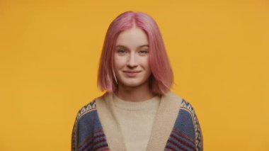 Sarı arka planda pembe saçlı ve diş telli neşeli bir kadın portresi.