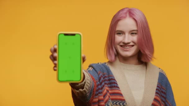 一个有着粉色头发的快乐学生 带着一个黄色背景的绿色屏幕着色键的电话 — 图库视频影像
