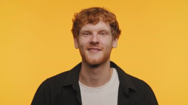 Neşeli kızıl saçlı adam parlak sarı bir arka plana göz kırpıyor.