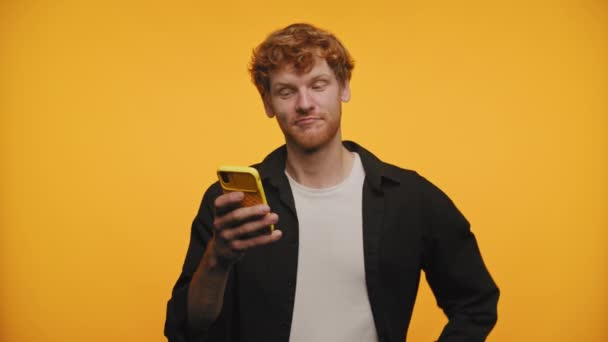 Rothaariger Mann Mit Telefon Nachdenklicher Geste Gelbem Hintergrund — Stockvideo