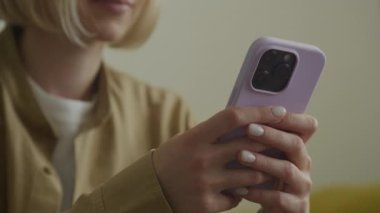 Kapalı mekanda mor bir akıllı telefon tutan kadın ellerine yakın çekim