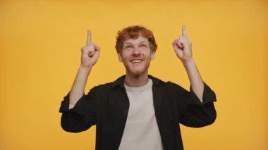 Gülümseyen ve işaret eden kızıl saçlı neşeli genç adam.