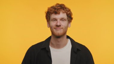 Sarı arka planda neşeli sırıtan kızıl saçlı adam.