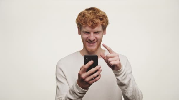 Радостный Рыжий Мужчина Смотрит Свой Телефон Удивленным Счастливым Выражением — стоковое видео