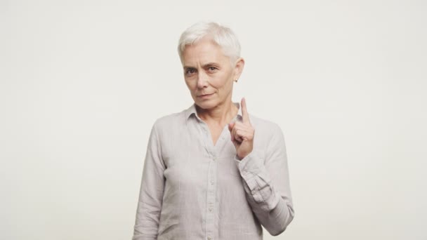 ポインティングジェスチャー 注意を伝える または警告を発する高齢女性 柔らかい白い背景 — ストック動画