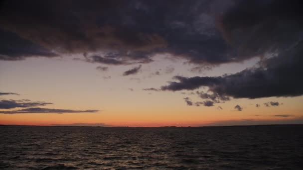 鮮やかなオレンジ色の静かな夕日が 海を渡るムードな雲の中を覗く — ストック動画