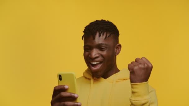 Πληθωρικός Νεαρός Άνδρας Μια Θριαμβευτική Χειρονομία Ενθουσιασμένοι Κοιτάζοντας Smartphone Του — Αρχείο Βίντεο
