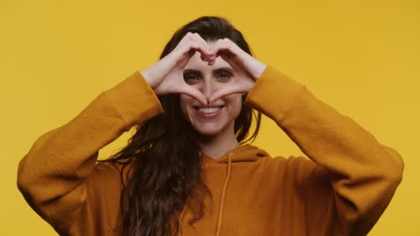 Uśmiechnięta Kobieta Musztardowej Bluzie Ukształtowała Serce Rękami Nad Oczami Odizolowana — Wideo stockowe