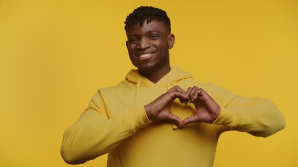 Jovem Sorridente Capuz Amarelo Fazendo Uma Forma Coração Com Mãos — Vídeo de Stock