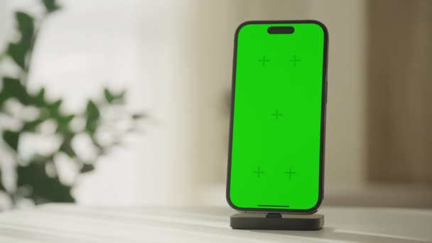 垂直智能手机站在一个带有绿色屏幕的充电平台上 理想的图形插入 在白色表面上 — 图库视频影像