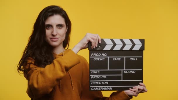 Hardal Kapüşonlu Neşeli Kadın Sarı Bir Fonda Çırpma Tahtası Tutuyor — Stok video
