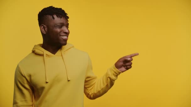 Sarı Kapüşonlu Neşeli Adam Sağı Işaret Ediyor Sarı Üzerine Izole — Stok video