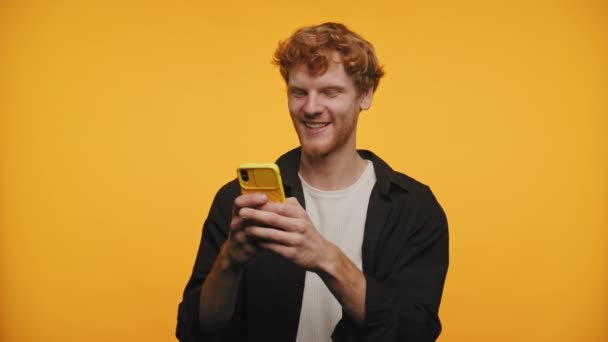 Joven Sonriente Centrado Mensajes Texto Con Teléfono Amarillo Brillante Sobre — Vídeos de Stock