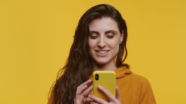 Woman Browsing Online Using Smartphone Cheerful Emotion Isolated Yellow Background — Stock Video