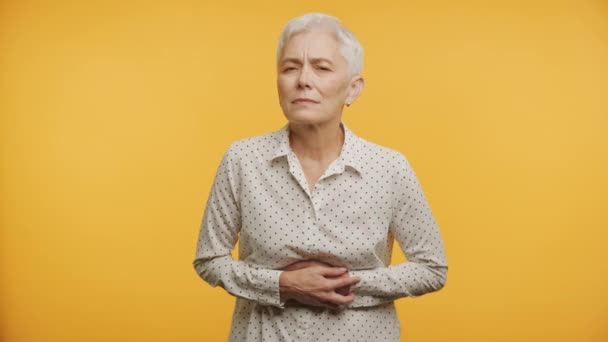Pacjentka Podeszłym Wieku Grymasząca Ból Brzucha Izolowana Żółtym Tle — Wideo stockowe