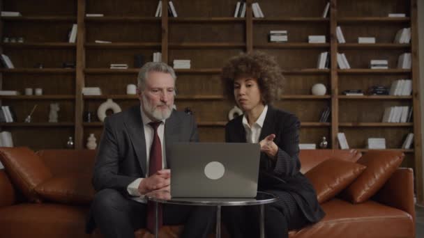 成熟した男性幹部と若い女性のプロフェッショナルが現代のオフィス環境でラップトップ上の情報を調べながらビジネス戦略を議論 — ストック動画