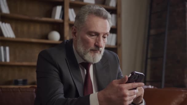 Ώριμος Επιχειρηματίας Κοστούμι Επικεντρωμένο Στο Smartphone Του Κάθεται Ένα Σύγχρονο — Αρχείο Βίντεο