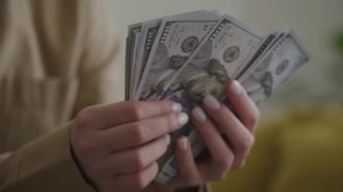 Yakın plan kadın elleri 100 dolarlık banknotları sayıyor, zenginliği ve mali yönetimi simgeliyor.