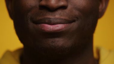 Neşeli bir Afrikalı Amerikalının gülüşünü yakından çek, parlak sarı bir arka plana karşı beyaz dişlerini göster.