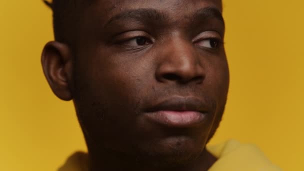 思慮深い若い黒人のプロフィールビューは 明るい黄色の背景に設定され 彼の熟考的な表現と詳細な顔の特徴を強調しています — ストック動画