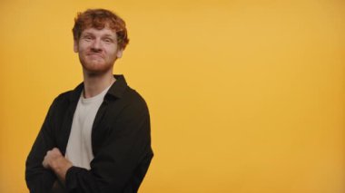 Sarı arka planda kızıl saçlı, gülümseyen adam.