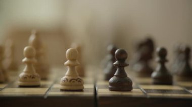 Ahşap bir satranç tahtasındaki beyaz ve siyah piyonların detaylı yakın plan çekimleri, yumuşak odaklı arka plan
