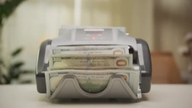 100 dolarlık banknotları dolly zoom çekimine sokan bir para sayma makinesinin yakın çekimi.