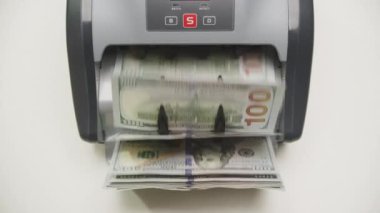 Hareket halindeki 100 dolarlık banknotları sayan bir para sayma makinesine yakın çekim