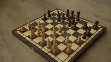 Tahta bir satranç tahtası. Oyulmuş satranç taşları. Oyunun ortasında ahşap bir yüzeye yerleştirilmiş.