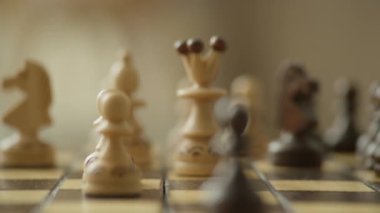 Satranç tahtasındaki ahşap satranç kraliçesinin yakın plan görüntüsü ve arka planda biraz bulanık olan diğer parçalar.