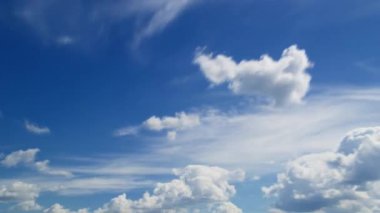 Pofuduk beyaz bulutlarla kaplı berrak mavi bir gökyüzü, sakin ve sakin bir atmosfer zaman dilimini betimliyor.