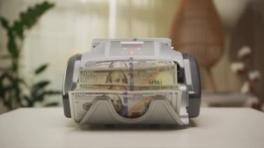 Para sayma makinesi beyaz bir yüzey üzerinde 100 dolarlık banknotları işleme