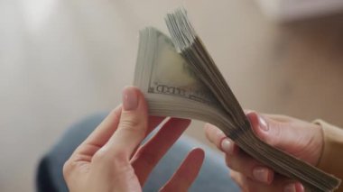 Eller yakın plan çekimde 100 dolarlık banknotları çeviriyor.
